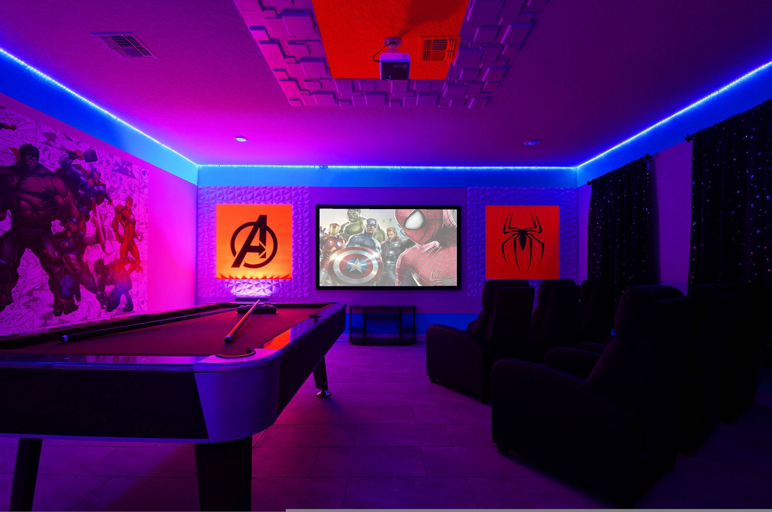 A room with a pool table, a large screen, and wall art featuring superhero characters.