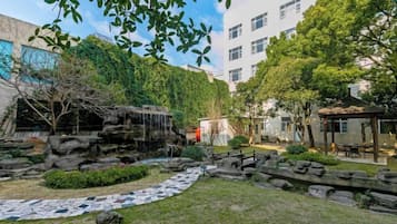 Un patio con jardín de rocas, una cascada pequeña y un sendero pavimentado.