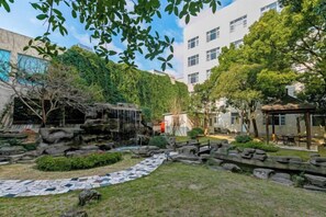 A courtyard with a rock garden, a small waterfall, and a paved walkway. - NEW OVERSEAS CHINESE HOTEL (Zhoushan)