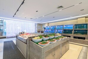 Una cocina de hotel moderna con un sistema de bufé, que presenta diferentes estaciones de comida y acuarios.