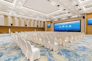 A conference room with rows of white chairs, a large screen, and a patterned carpet. - NEW OVERSEAS CHINESE HOTEL (Zhoushan)