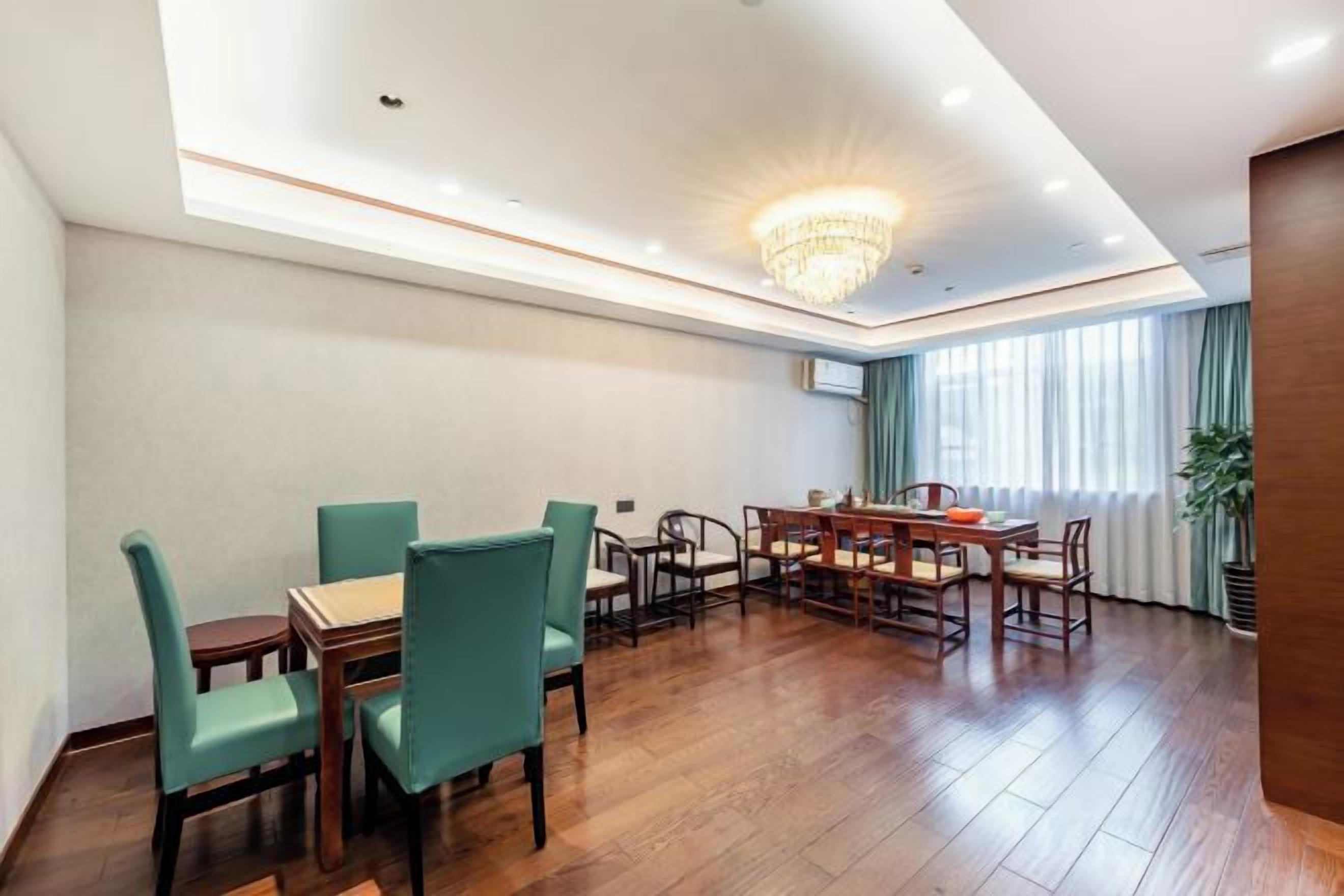 Un comedor de hotel con suelo de madera, un candelabro y un ventanal con cortinas.