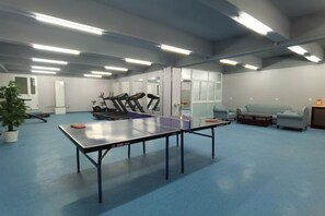 A spacious room with a ping pong table, exercise equipment, and seating areas. - NEW OVERSEAS CHINESE HOTEL (Zhoushan)