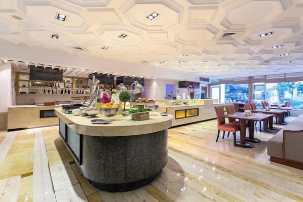 A hotel lobby with a central bar area, seating arrangements, and a view through the windows.