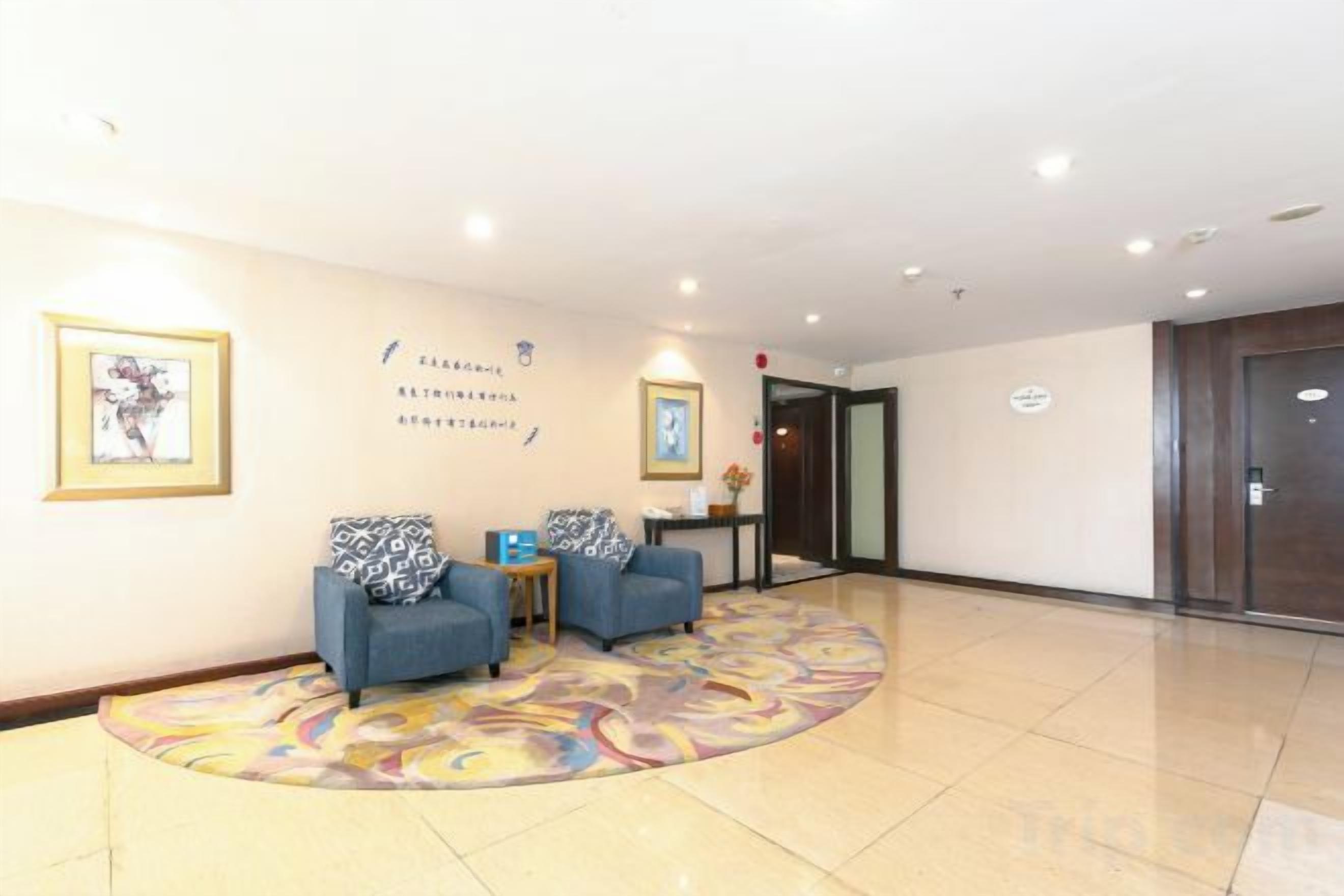 A hotel lobby with two armchairs, a small table, and a reception desk.