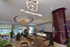 A modern coffee shop interior with a bar area, seating, and a large wooden column. - NEW OVERSEAS CHINESE HOTEL (Zhoushan)