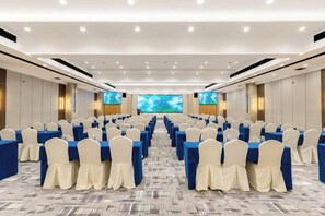 A conference room with rows of tables and chairs, large screens, and a carpeted floor. - NEW OVERSEAS CHINESE HOTEL (Zhoushan)
