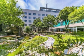 A courtyard with a fountain, trees, and a building with multiple windows. - NEW OVERSEAS CHINESE HOTEL (Zhoushan)