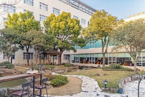 A courtyard with a gazebo, stone pathway, and outdoor seating area. - NEW OVERSEAS CHINESE HOTEL (Zhoushan)