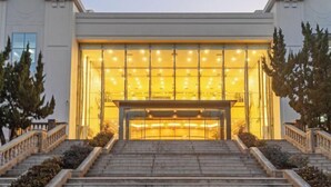 Un edificio con una entrada imponente, que presenta una amplia escalera que conduce a un acceso luminoso y espacioso.