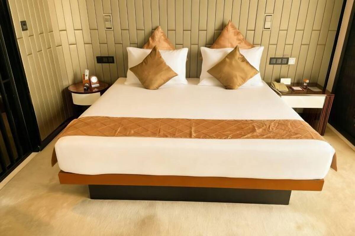 A hotel room with a large bed, two bedside tables, and a wall with vertical paneling.