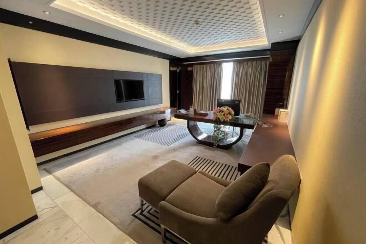 A modern living room with a sofa, a TV, a glass coffee table, and a decorative vase.