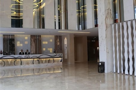 A modern hotel lobby with a reception desk, marble flooring, and large windows.. Dongfang Mingyuan Hotel