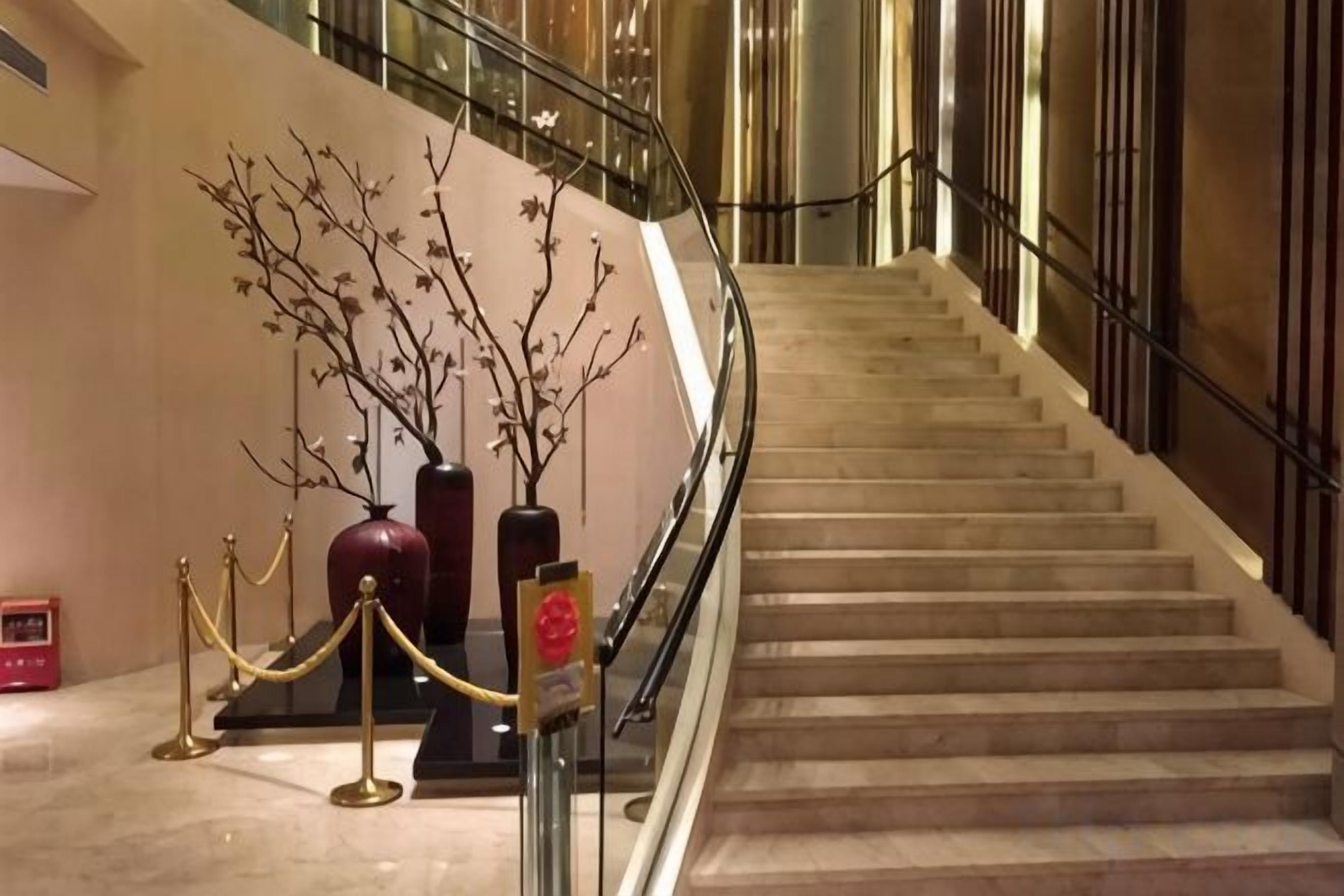 Eine Marmortreppe mit Handlauf, die zu einer oberen Etage führt.