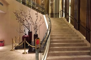 A marble staircase with a handrail, leading to an upper floor.