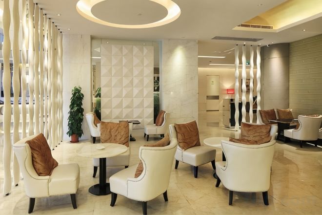 Un área de estar moderna con sofás blancos, una mesa redonda y una planta decorativa.