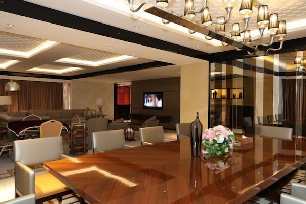 A modern hotel conference room with a large wooden table, comfortable seating, a television, and ambient lighting. - Dongfang Mingyuan Hotel (Longchuan)