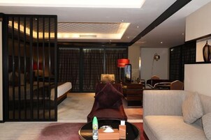 Una habitación de hotel moderna con un sofá, una silla, una mesa de centro y un televisor.