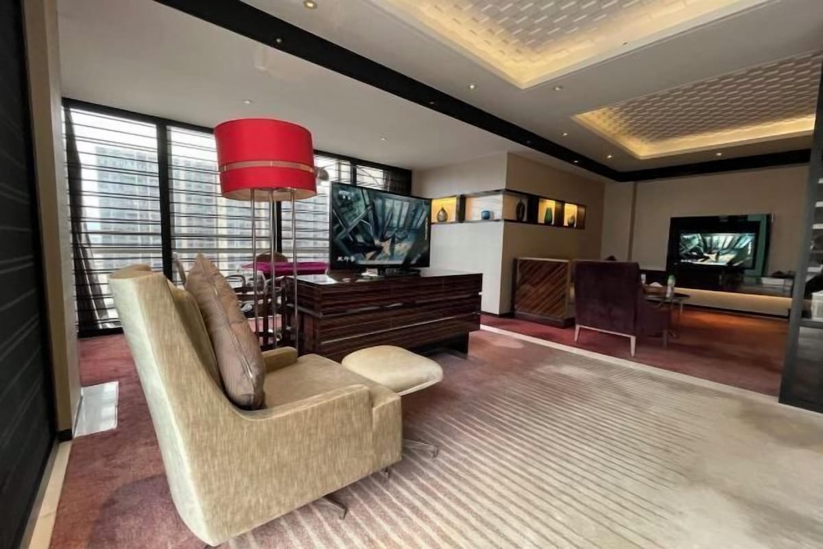 A modern living room with a sofa, a red floor lamp, a TV, and a fireplace.