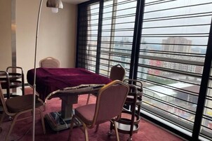 Una habitación con una mesa de comedor, sillas, una ventana con persianas y vistas a edificios.