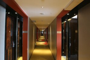 En hotelgang med døre på begge sider, et tæppe på gulvet og en rød løber til enden.