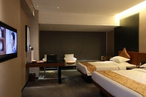 A hotel room with two beds, a desk with a chair, a TV, and a large wall-mounted TV. - Dongfang Mingyuan Hotel (Longchuan)