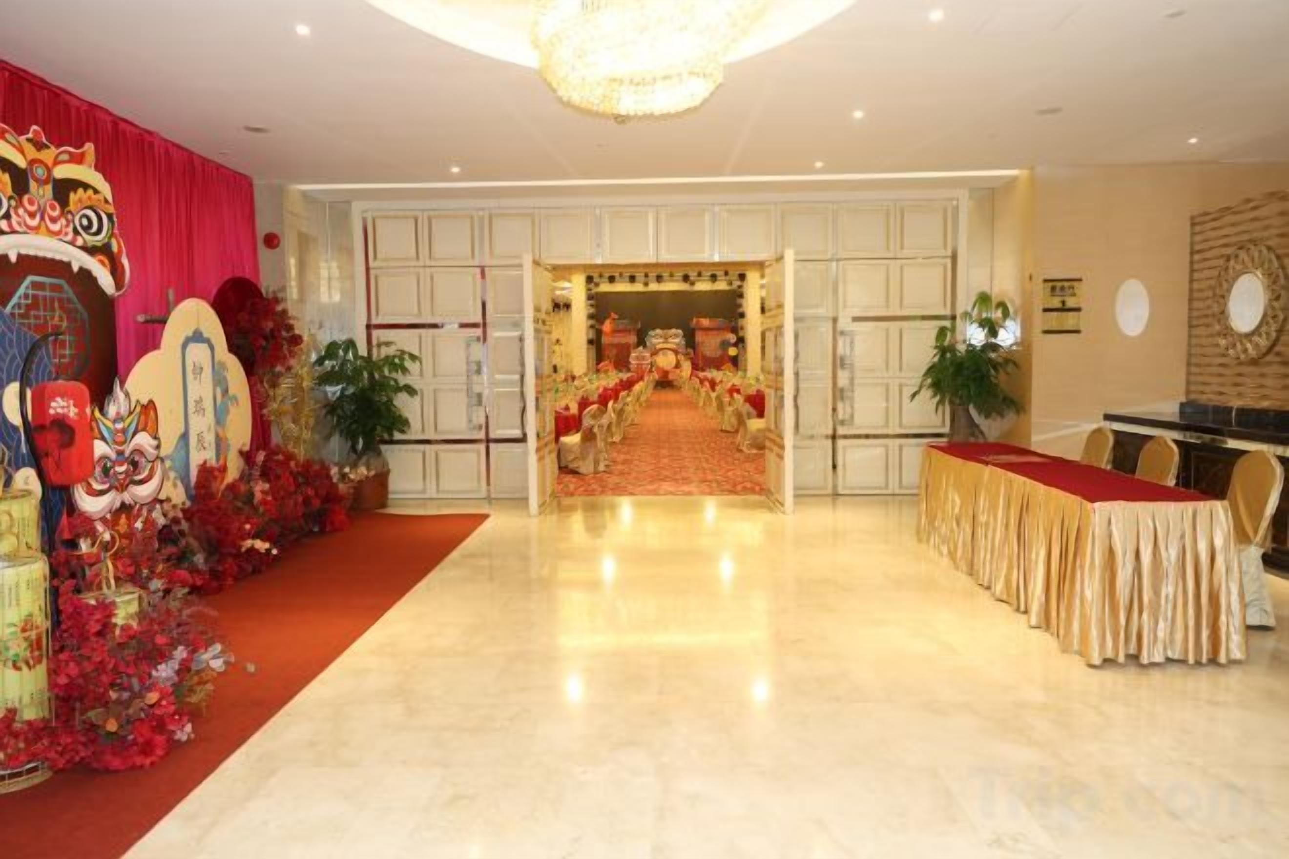 Un hall de hotel con alfombra roja, una recepción y una entrada decorativa.