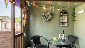 A cozy outdoor seating area with wicker chairs, a round table, and a heart-shaped decoration on the wall. - 'Haworth Haven', Warm Winter Cottage Getaway in Yorkshire (Haworth)