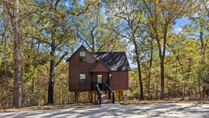 Une cabane avec une façade en bois, un petit porche et un escalier menant à l’entrée.