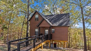 Une cabane en bois dotée d’un balcon, entourée d’arbres.