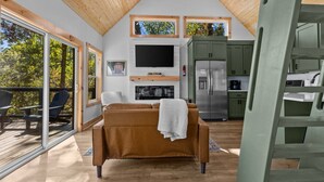 Un intérieur moderne avec un plafond en bois, un canapé marron, un téléviseur à écran plat et un coin cuisine.