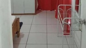 Een kamer met een witte kast, een rood gordijn, een metalen bed en een betegelde vloer.