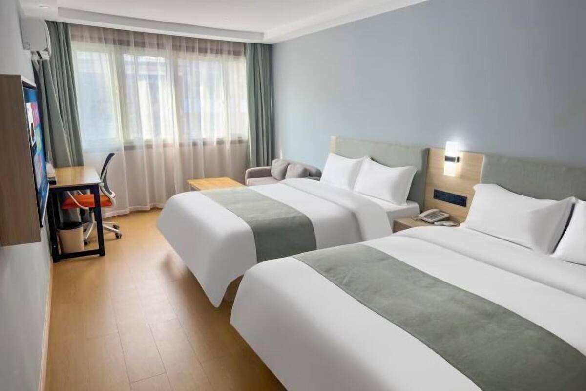 Una habitación de hotel con dos camas, un escritorio, una silla y un televisor.