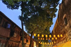 A street lined with traditional buildings and trees, with string lights hanging between them. - Vanyou Inn (Huzhou Nanxun Ancient Town Shiyuan Road) (Huzhou)