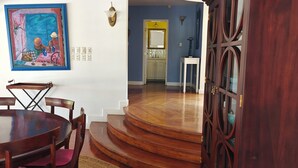Un comedor con una mesa y sillas de madera, un tapiz tejido y un cuadro en la pared.