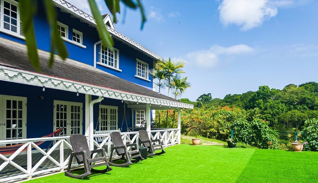 A two-story building with a porch, outdoor seating, and a well-maintained lawn.