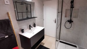 A modern bathroom with a glass-enclosed shower, a white sink, and a dark vanity. - 
Chic Studio in Old Bergerac (Bergerac)