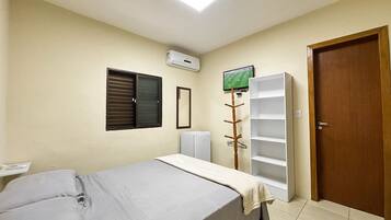 Quarto com cama, guarda-roupa, radiador, espelho e porta.
