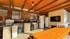 Una cocina con vigas de madera, estufa a gas, microondas, pileta y mesa de madera.