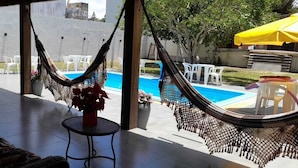 Zona junto a la piscina con una hamaca, asientos exteriores y vista al agua.
