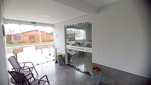 Zona de recepción con puerta de vidrio, mostrador de recepción y dos plantas en macetas.