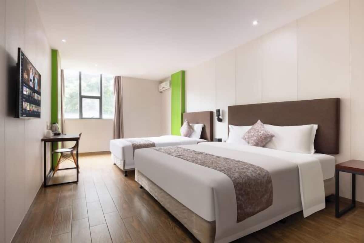 Una habitación de hotel con dos camas, un escritorio, una silla y un televisor.