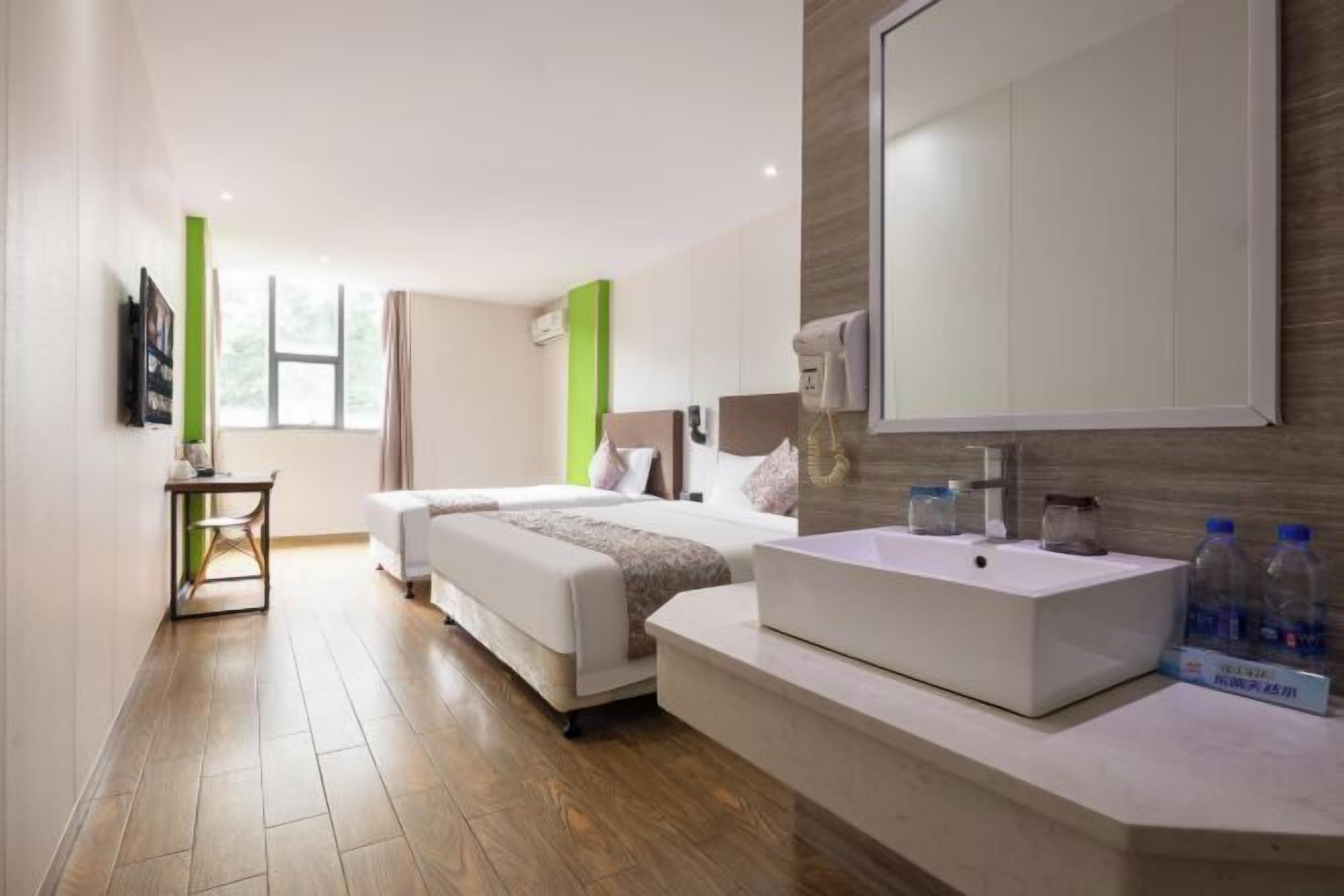 A hotel room with two beds, a large mirror, a sink, and a small table.