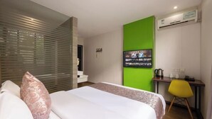 Ein Hotelzimmer mit Bett, Schreibtisch, Stuhl, Klimaanlage und Fernseher.