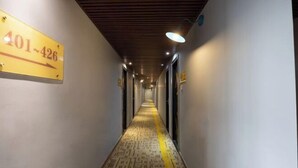 Ein Hotelgang mit einem Schild, das die Zimmernummern 401 bis 426 anzeigt. Der Gang ist gut beleuchtet und verfügt über einen Teppich mit Muster.