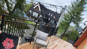 A wooden deck with two lounge chairs, one with a cushion and the other with a pillow.
