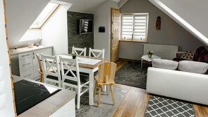 A compact living space with a dining area, kitchenette, and a seating area with a sofa.