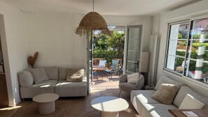 A modern living room with a sofa, two coffee tables, and a hanging light fixture.