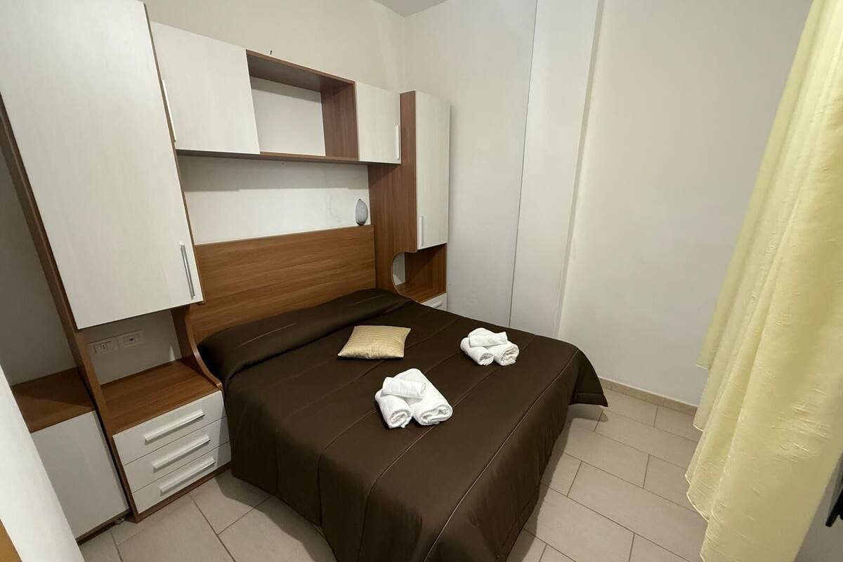 A hotel room with a bed, a nightstand, a wardrobe, and a bathroom curtain.