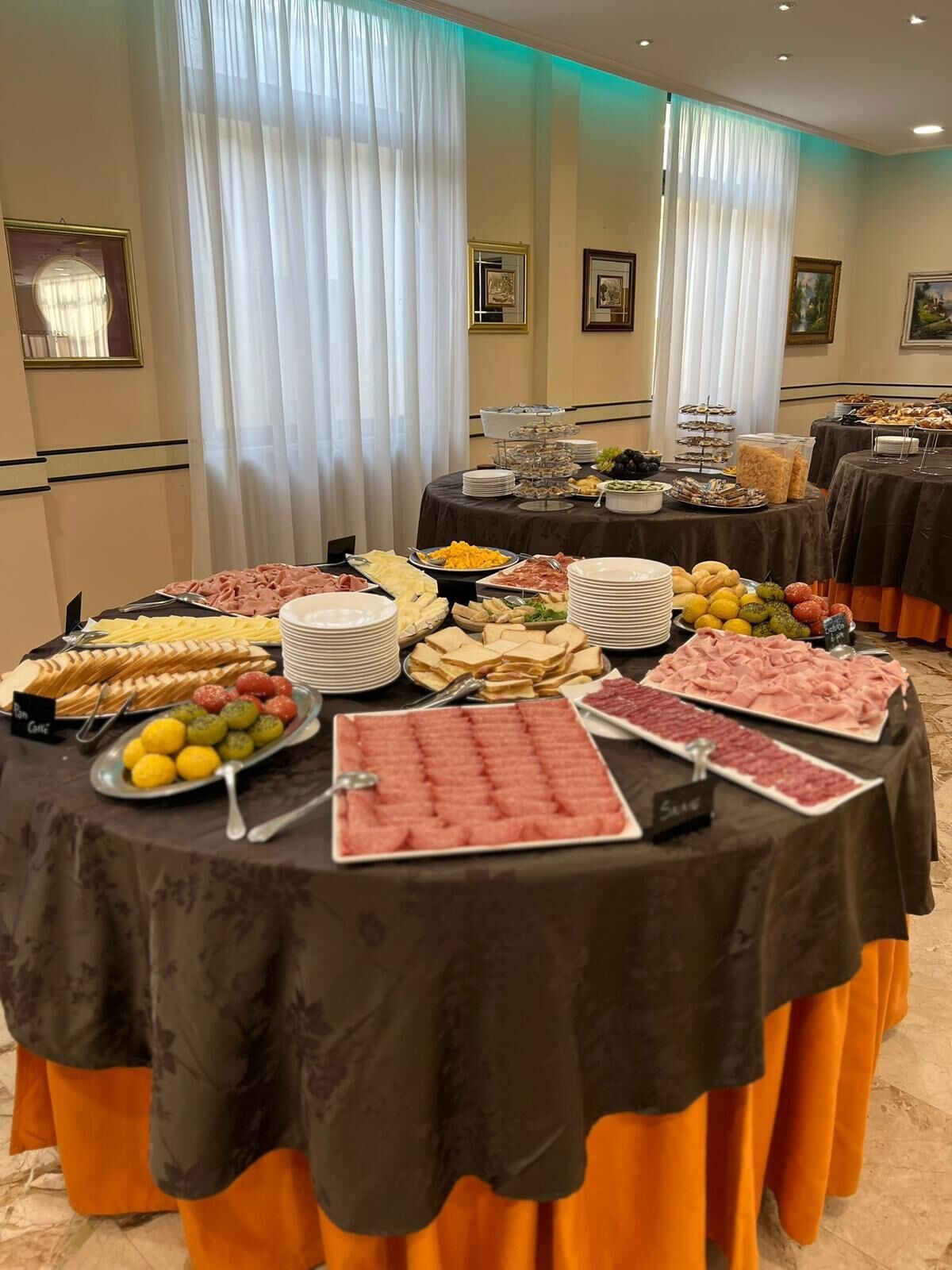 A buffet table with various food items and a sign indicating 'Sausage'.